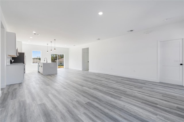 unfurnished living room with light hardwood / wood-style flooring and sink