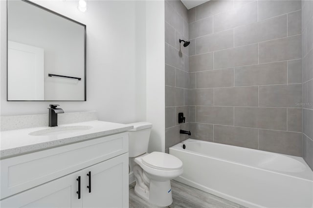 full bathroom featuring hardwood / wood-style floors, vanity, toilet, and tiled shower / bath