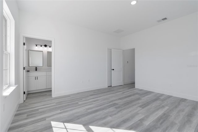 unfurnished bedroom featuring light hardwood / wood-style floors and connected bathroom