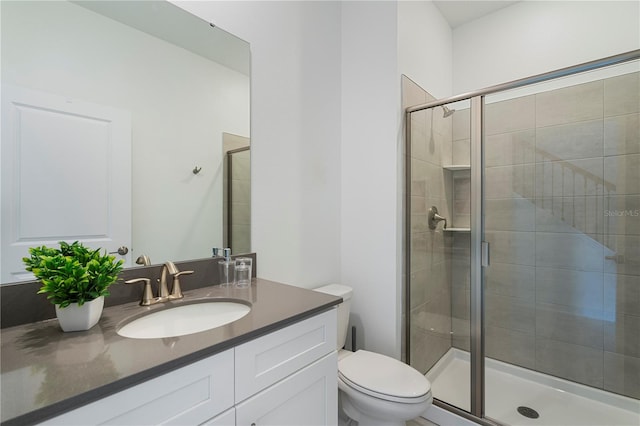 bathroom featuring a shower with door, vanity, and toilet