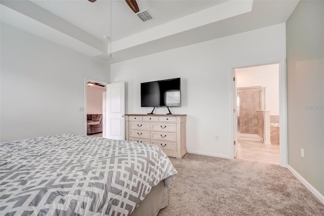 carpeted bedroom with ceiling fan, a raised ceiling, and connected bathroom