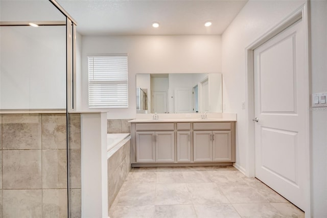 bathroom with vanity and tiled tub