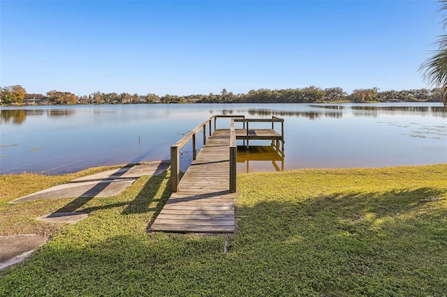 view of dock with a lawn and a water view