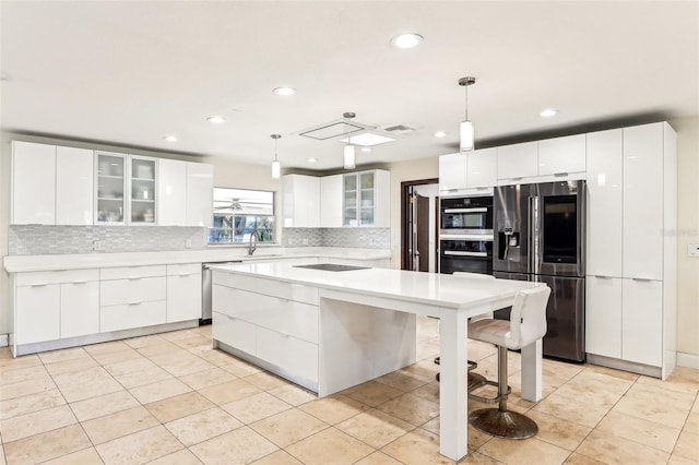 kitchen featuring white cabinets, stainless steel appliances, a kitchen island, and hanging light fixtures