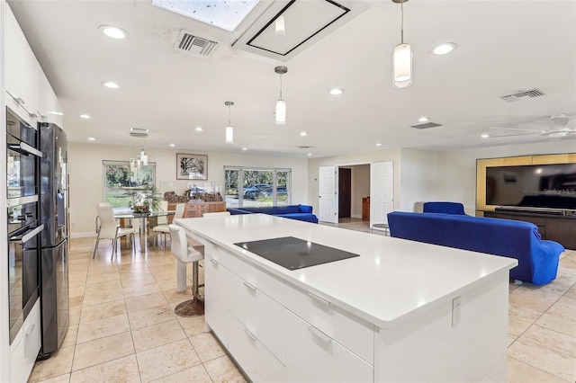 kitchen with white cabinetry, a center island, ceiling fan, hanging light fixtures, and black appliances