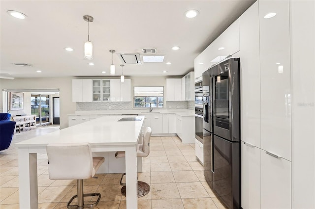 kitchen featuring pendant lighting, tasteful backsplash, a kitchen island, white cabinetry, and a breakfast bar area