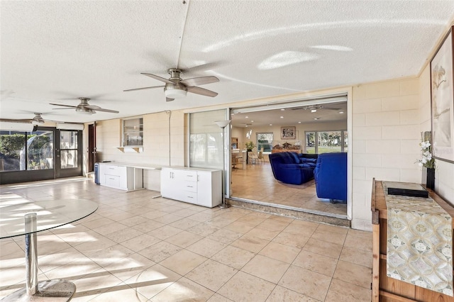 interior space featuring ceiling fan, light tile patterned flooring, a healthy amount of sunlight, and a textured ceiling