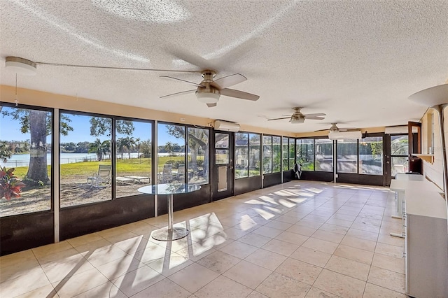 unfurnished sunroom featuring ceiling fan and a water view