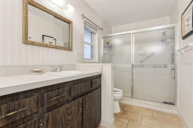 bathroom with tile patterned flooring, vanity, toilet, and walk in shower