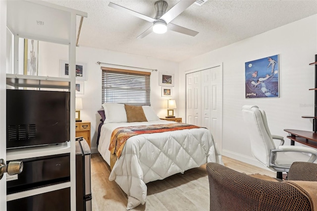 bedroom with a textured ceiling, ceiling fan, light hardwood / wood-style flooring, and a closet