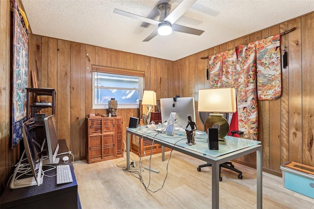 home office featuring a textured ceiling, ceiling fan, and wooden walls