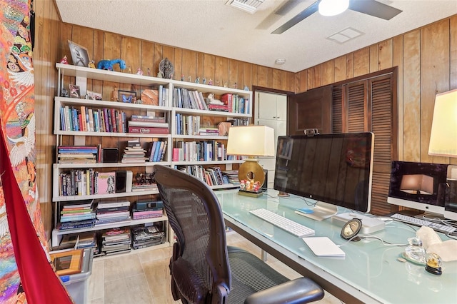 office space featuring a textured ceiling, ceiling fan, wooden walls, and light tile patterned flooring