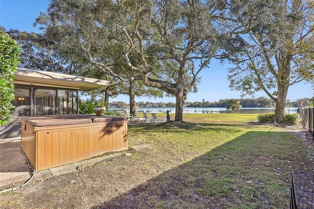 view of yard with a water view, a hot tub, and a sunroom