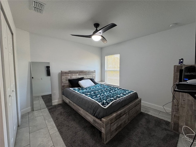 tiled bedroom with ceiling fan, a textured ceiling, and a closet