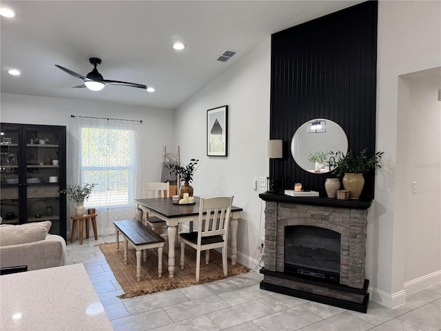 dining area with ceiling fan, light tile patterned floors, a fireplace, and lofted ceiling