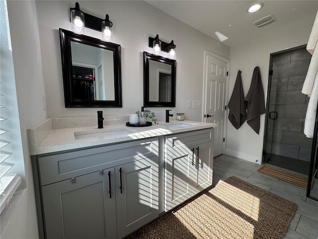 bathroom with a shower with door, vanity, and tile patterned flooring