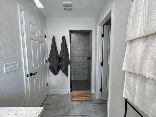 bathroom featuring a textured ceiling, tile patterned floors, and tiled shower