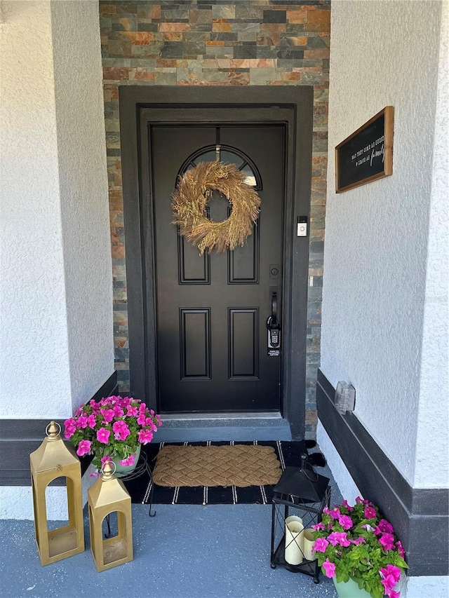 view of exterior entry with stone siding and stucco siding