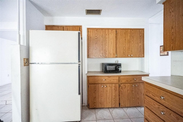 kitchen with light tile patterned flooring, a textured ceiling, and white refrigerator