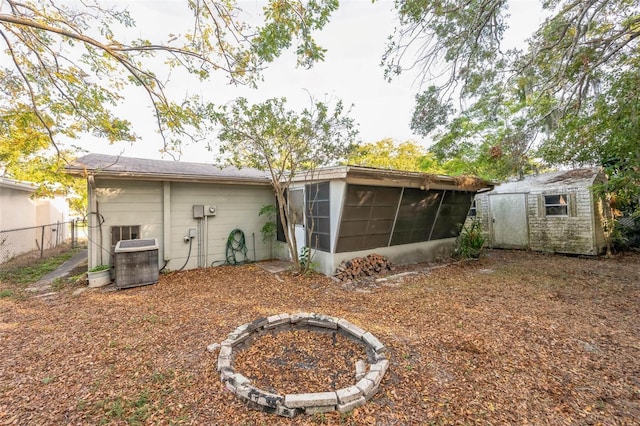 rear view of house with a sunroom, a storage shed, and central air condition unit