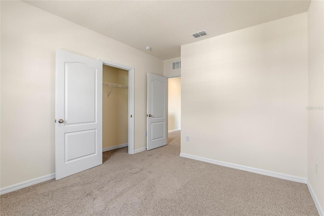 unfurnished bedroom with light carpet and a closet