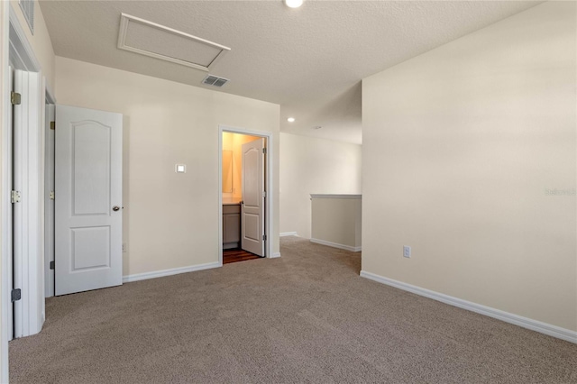 unfurnished bedroom with carpet flooring, ensuite bathroom, and a textured ceiling