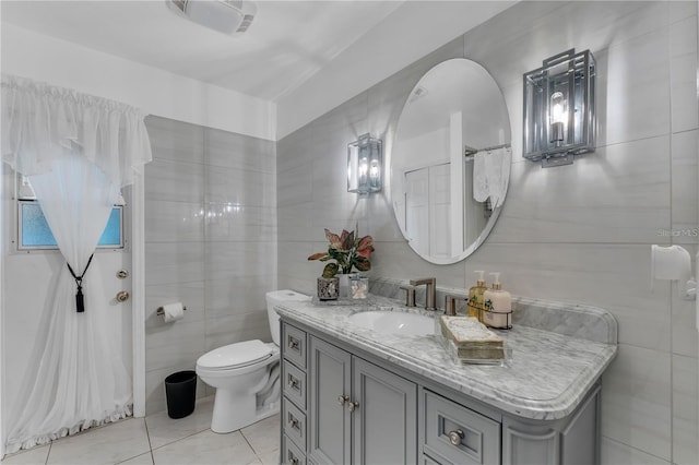 bathroom with tile patterned floors, vanity, tile walls, and toilet