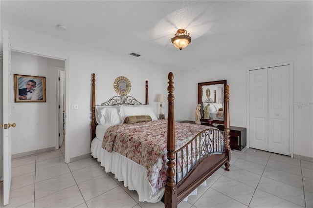 tiled bedroom with a textured ceiling and a closet