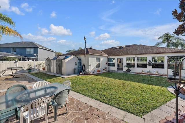 rear view of house with a storage unit, a patio area, and a yard