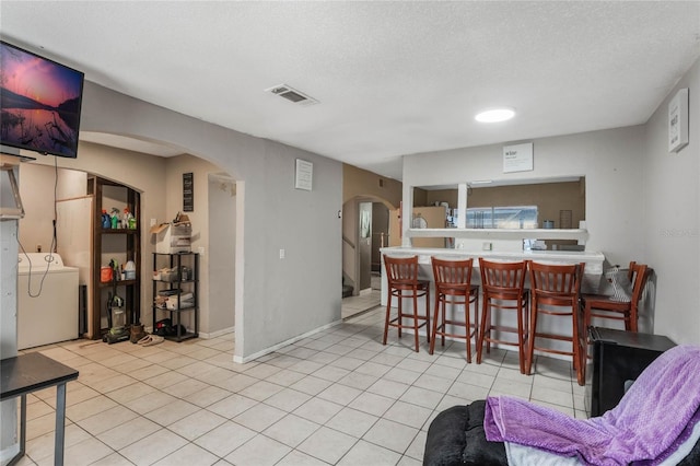 dining area featuring a textured ceiling, light tile patterned flooring, and washing machine and dryer