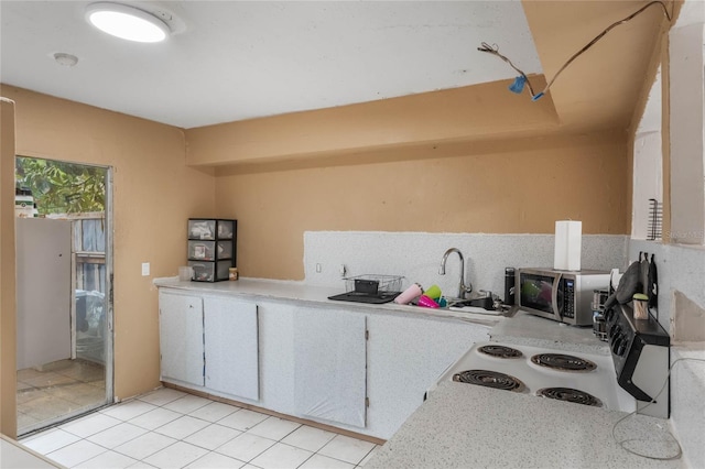 kitchen featuring light tile patterned floors, white cabinetry, range with electric stovetop, and sink