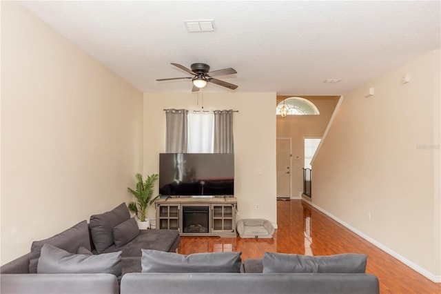 living room with ceiling fan, a fireplace, a textured ceiling, and light hardwood / wood-style flooring