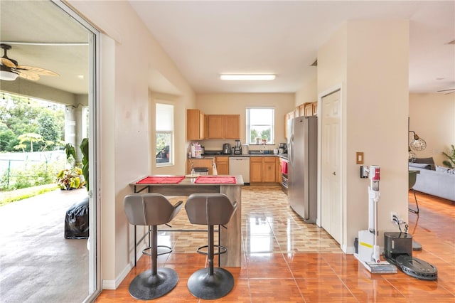 kitchen featuring stainless steel fridge, white dishwasher, ceiling fan, and a breakfast bar area