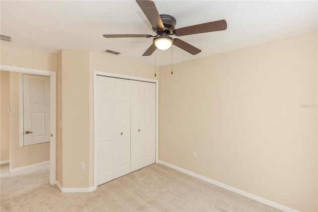 unfurnished bedroom featuring ceiling fan, light colored carpet, and a closet