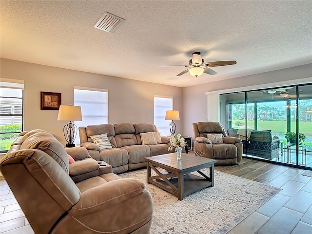 living area featuring ceiling fan, a textured ceiling, and visible vents