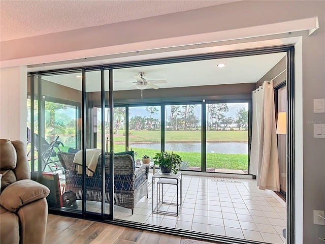 entryway with a textured ceiling, a water view, wood finished floors, and a wealth of natural light