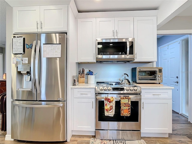 kitchen with appliances with stainless steel finishes, white cabinets, and a toaster