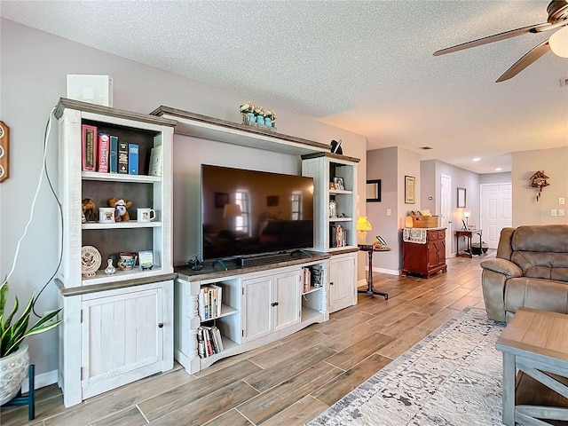 living room featuring wood tiled floor, ceiling fan, a textured ceiling, and baseboards