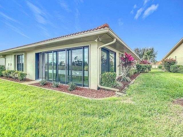 view of side of property featuring a lawn and stucco siding