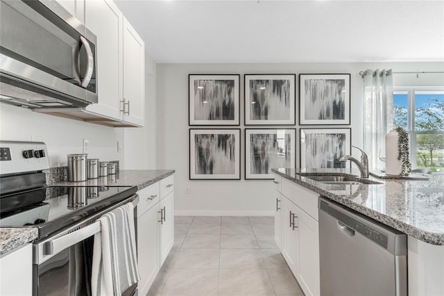 kitchen featuring stone counters, white cabinets, sink, appliances with stainless steel finishes, and light tile patterned flooring