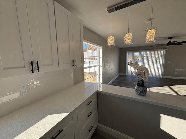 kitchen with a healthy amount of sunlight, decorative backsplash, white cabinetry, and pendant lighting