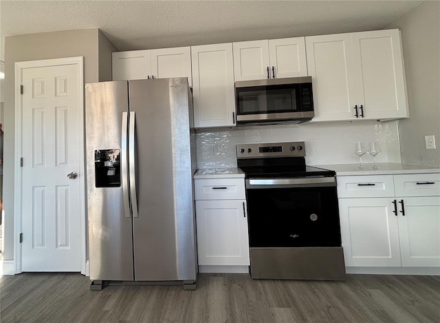 kitchen featuring white cabinetry, tasteful backsplash, dark hardwood / wood-style flooring, a textured ceiling, and appliances with stainless steel finishes