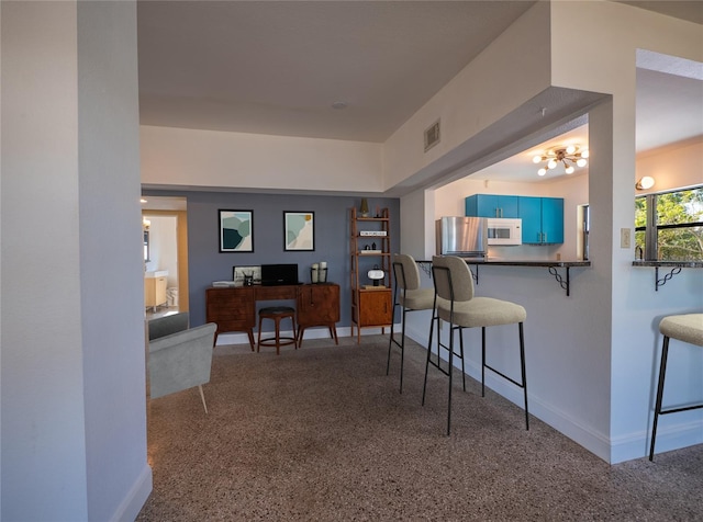 interior space featuring stainless steel refrigerator, kitchen peninsula, blue cabinetry, and a kitchen breakfast bar