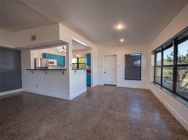 unfurnished living room featuring plenty of natural light and a notable chandelier