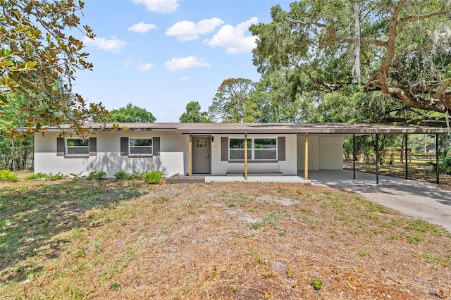 single story home with covered porch, a carport, and a front yard