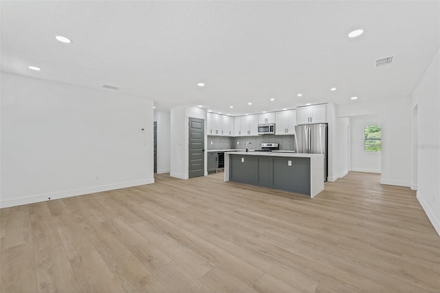 kitchen with a center island, light hardwood / wood-style flooring, tasteful backsplash, white cabinetry, and stainless steel appliances