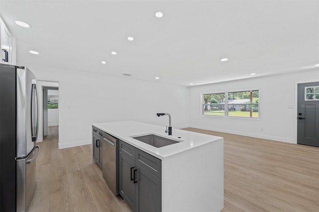 kitchen featuring gray cabinetry, sink, light hardwood / wood-style flooring, a kitchen island with sink, and appliances with stainless steel finishes