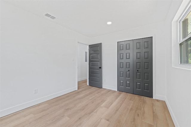 unfurnished bedroom with light wood-type flooring and a closet