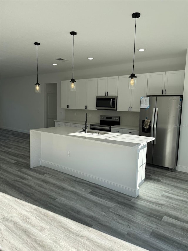 kitchen with pendant lighting, white cabinetry, light hardwood / wood-style flooring, a kitchen island with sink, and appliances with stainless steel finishes