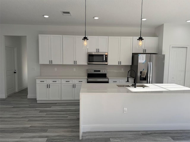 kitchen featuring white cabinetry, sink, pendant lighting, and appliances with stainless steel finishes